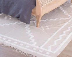 Tapis beige tissé main et motifs brodés blancs "Matis" format 120x180cm